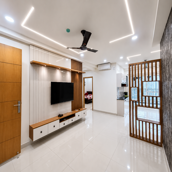 Modern living room, luxury interior, contemporary home, spacious living area, elegant apartment, stylish interior, TV unit, wall mounted TV, wooden TV panel, wooden wall decor, floating TV cabinet, storage cabinets, modern furniture, minimalist design, white walls, glossy flooring, tiled floor, ceiling fan, LED strip lighting, false ceiling, recessed lighting, bright room, air conditioner, wooden door, wooden partition, decorative room divider, vertical wooden slats, open layout, dining area, kitchen area, apartment interior, high rise apartment, city view, balcony window, glass windows, natural light, premium home, luxury apartment, residential property, modern architecture, clean interior, neat living room, contemporary decor, wooden accents, neutral color palette, polished floor, spacious apartment, urban lifestyle, home decoration, elegant living space, real estate interior.